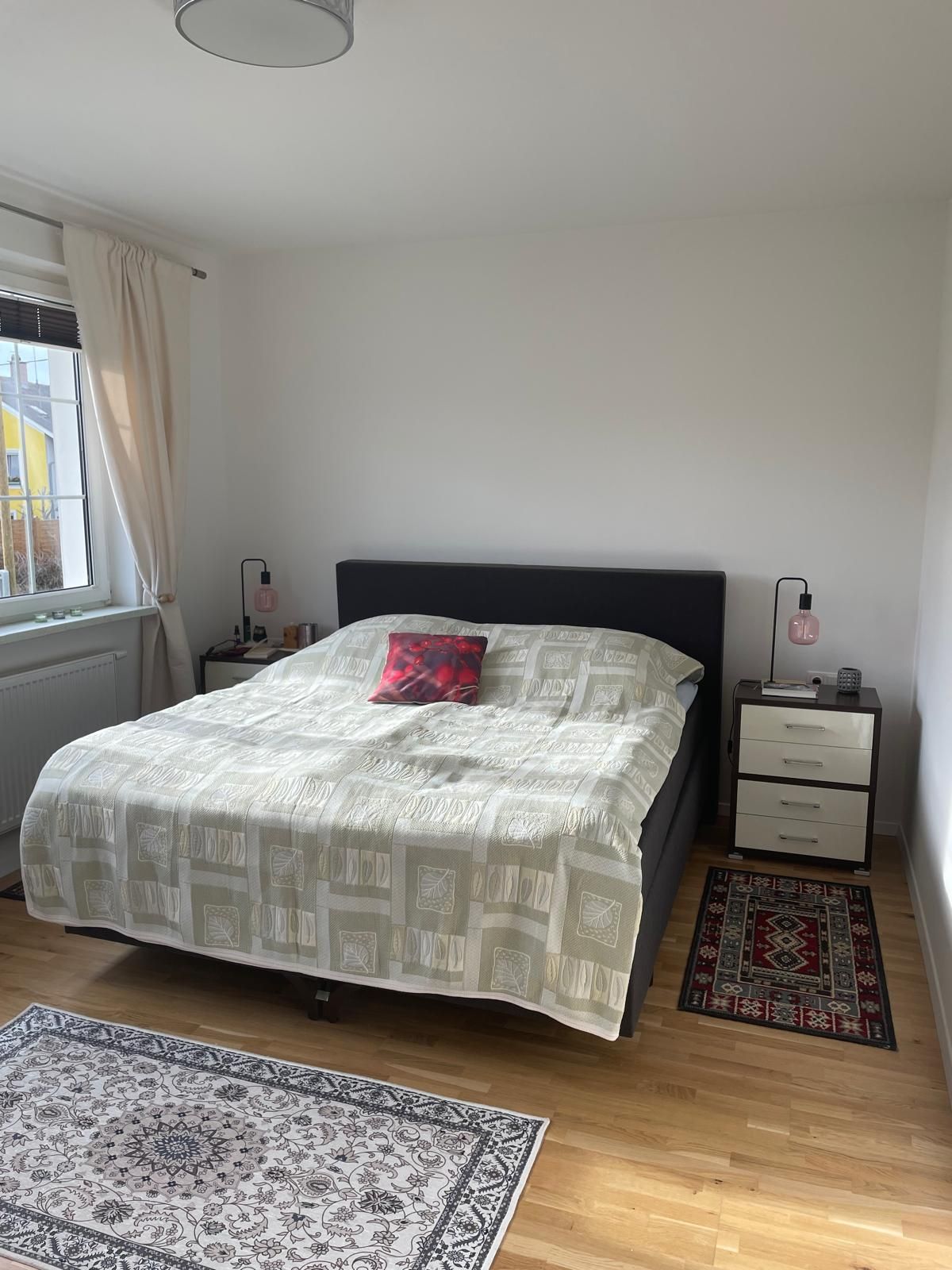 Ein Schlafzimmer mit einem Doppelbett, zwei Nachttischen und Teppichen auf Holzboden.