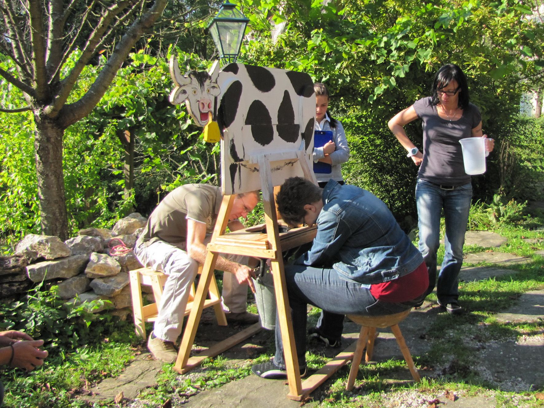 Personengruppe bei Teambuildingspielen, melken eine Holzkuh