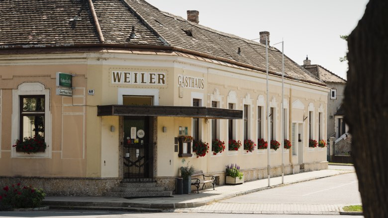 Historisches Gasthaus Weiler in Laa an der Thaya mit blumengeschmückten Fenstern.