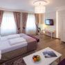 Elegantes Hotelzimmer mit Doppelbett, Schreibtisch, TV und Obstteller.