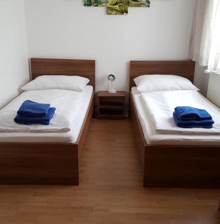 Zwei Einzelbetten in einem Zimmer mit Wanddekoration und blauen Handt&uuml;chern.