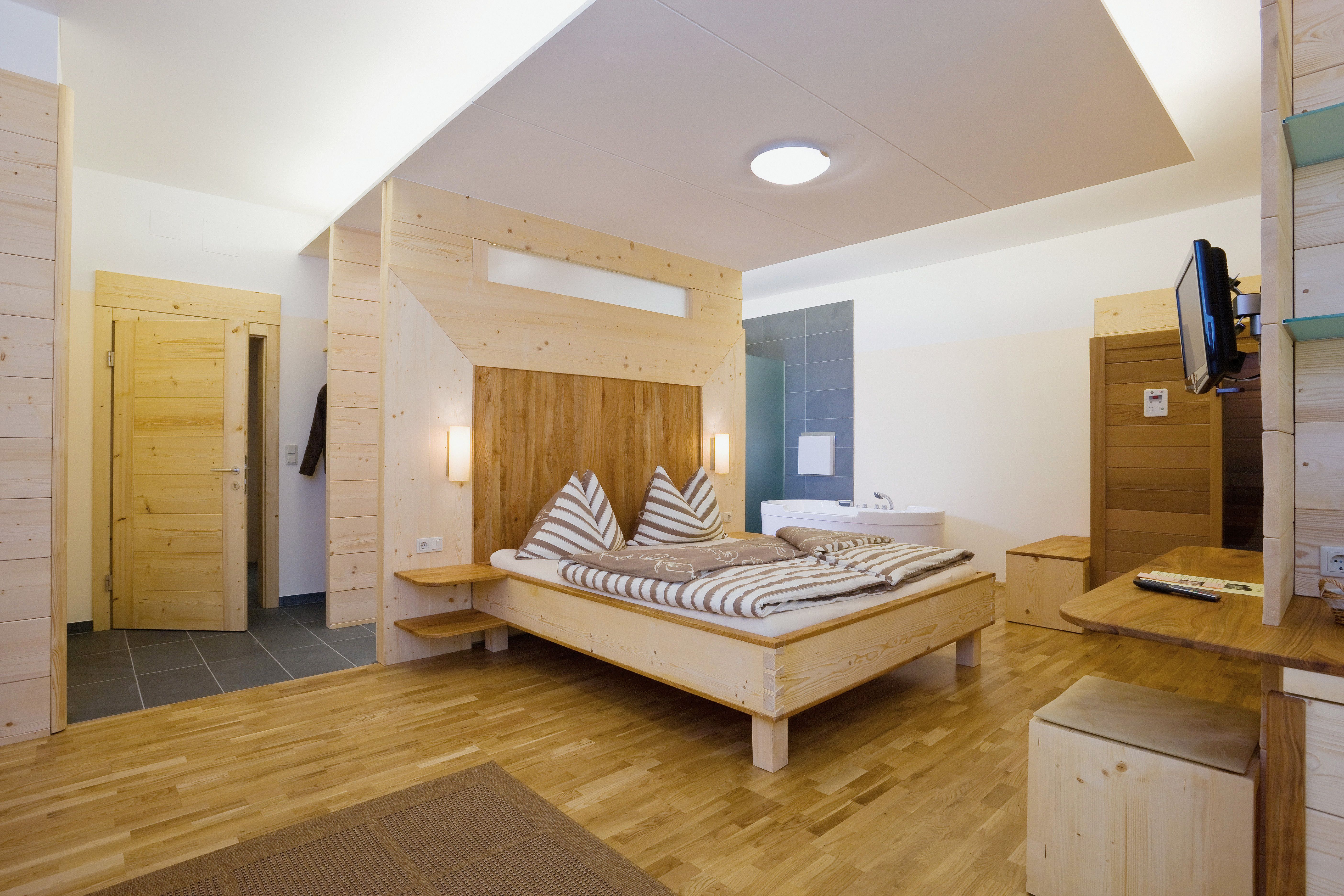 Holzinterieur eines modernen Hotelzimmers mit Doppelbett und Badewanne.