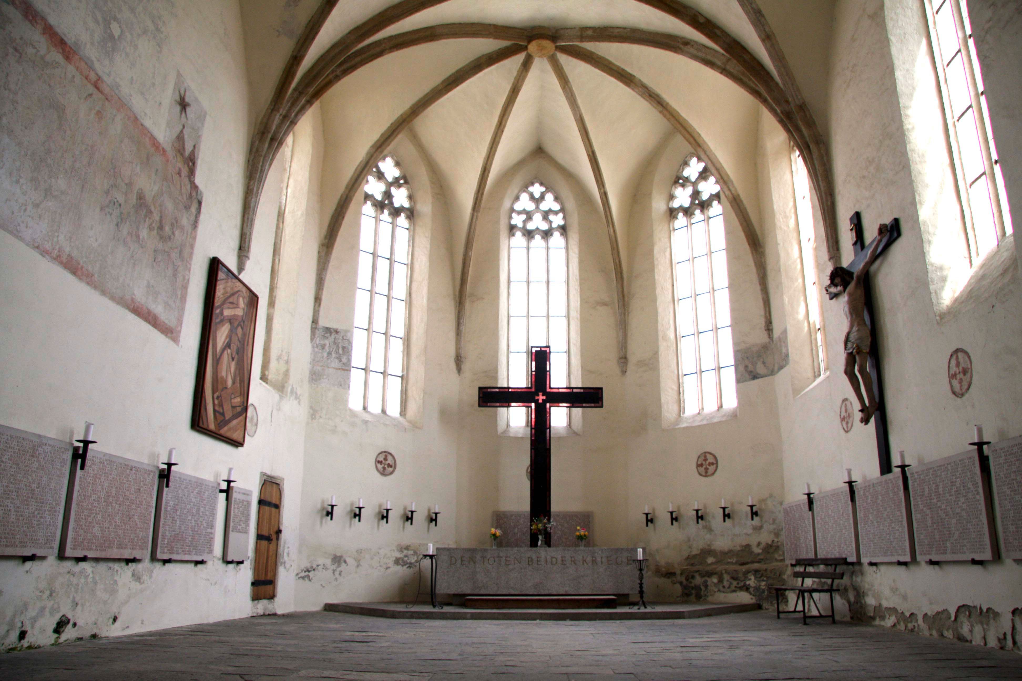 Innenansicht der Frauenbergkirche Stein mit gotischen Fenstern und einem großen Kreuz.