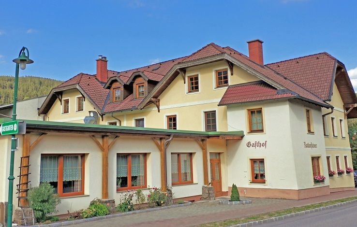 Ein traditioneller Gasthof mit gelber Fassade und roten Dächern.