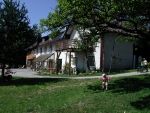 Ein traditionelles Bauernhaus mit Holzbalkon und grünem Garten im Vordergrund.