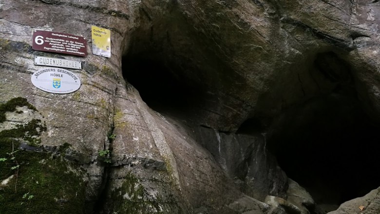 Eingang der Gudenush&ouml;hle mit Schildern an der Felswand.