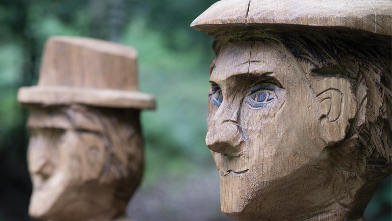 Zwei Holzskulpturen von Sagenfiguren mit H&uuml;ten in Lanzenkirchen.