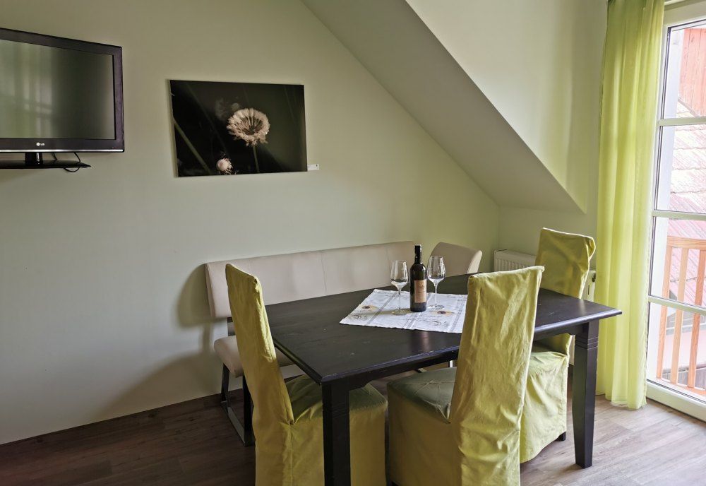 Essbereich in einer Ferienwohnung mit Tisch, Stühlen und Weinflasche.