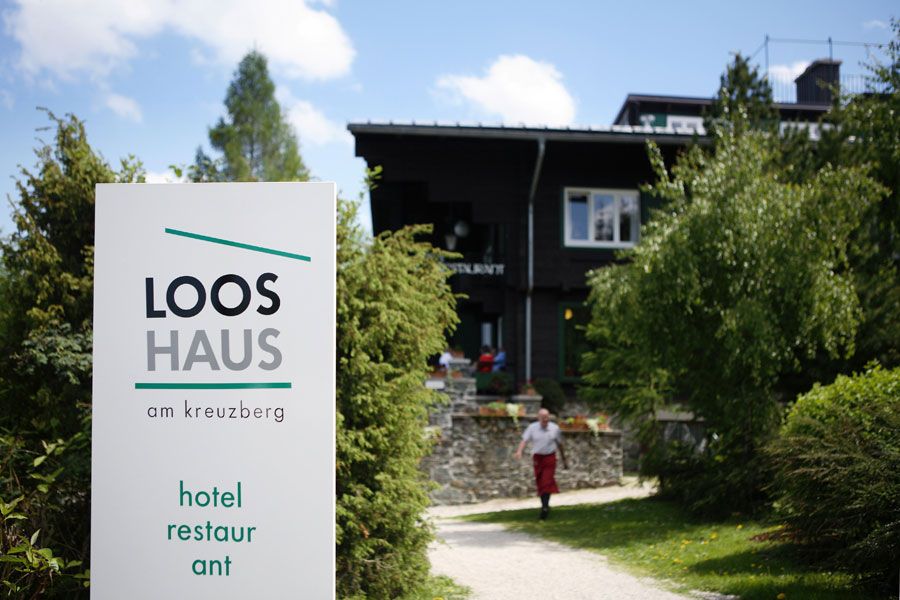 Eingang des Looshauses am Kreuzberg mit Schild und Garten.