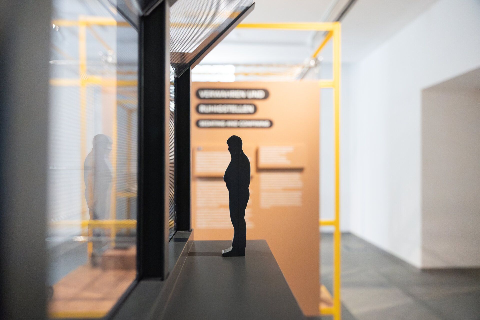 Silhouette einer menschlichen Figur als Ausstellungsobjekt der Niederösterreichischen Landesausstellung 2026, gespiegelt in einer Glasfläche, mit Infotafeln zum Thema Wahrnehmung im Hintergrund.