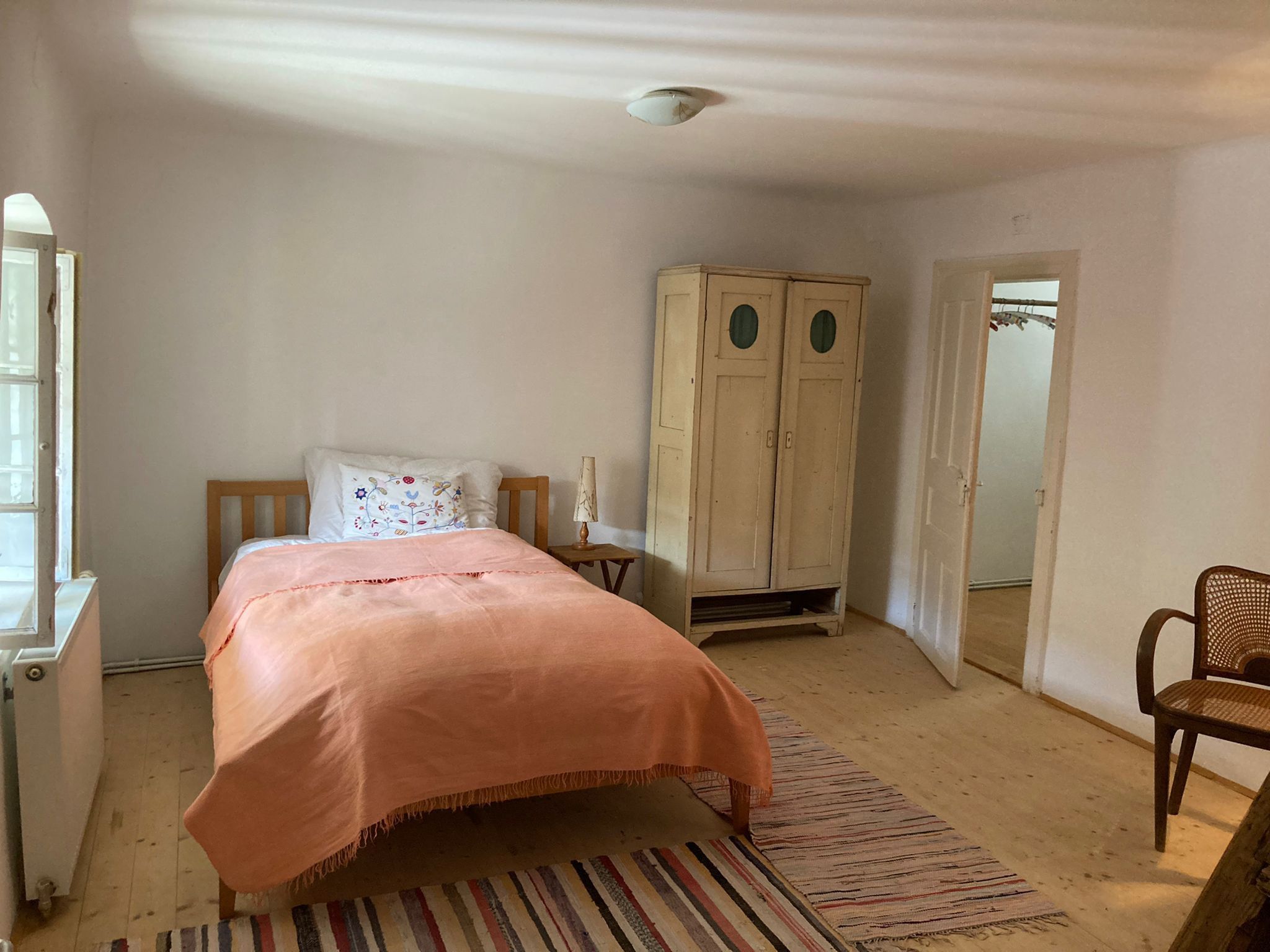 Bett mit orangener Bettwäsche, einem alten Schrank und einer alten Tür.