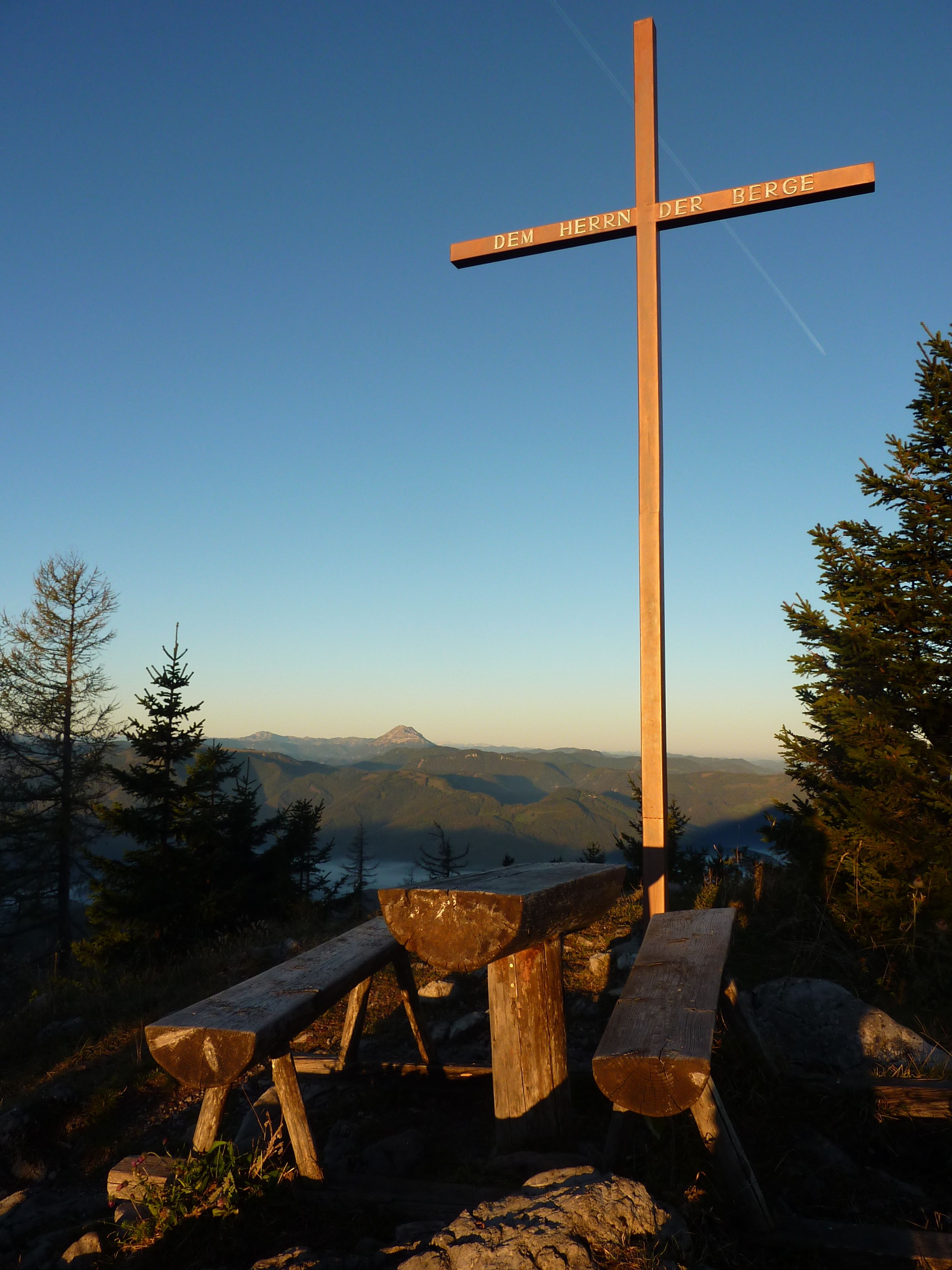 Gipfelkreuz am Türnitzer Höger mit Holzbänken und Bergpanorama im Hintergrund.