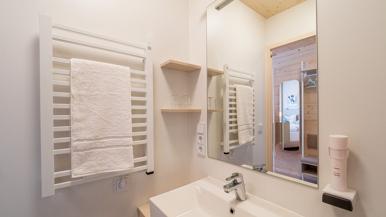 Modernes Badezimmer mit Handtuchhalter, Spiegel und Waschbecken.