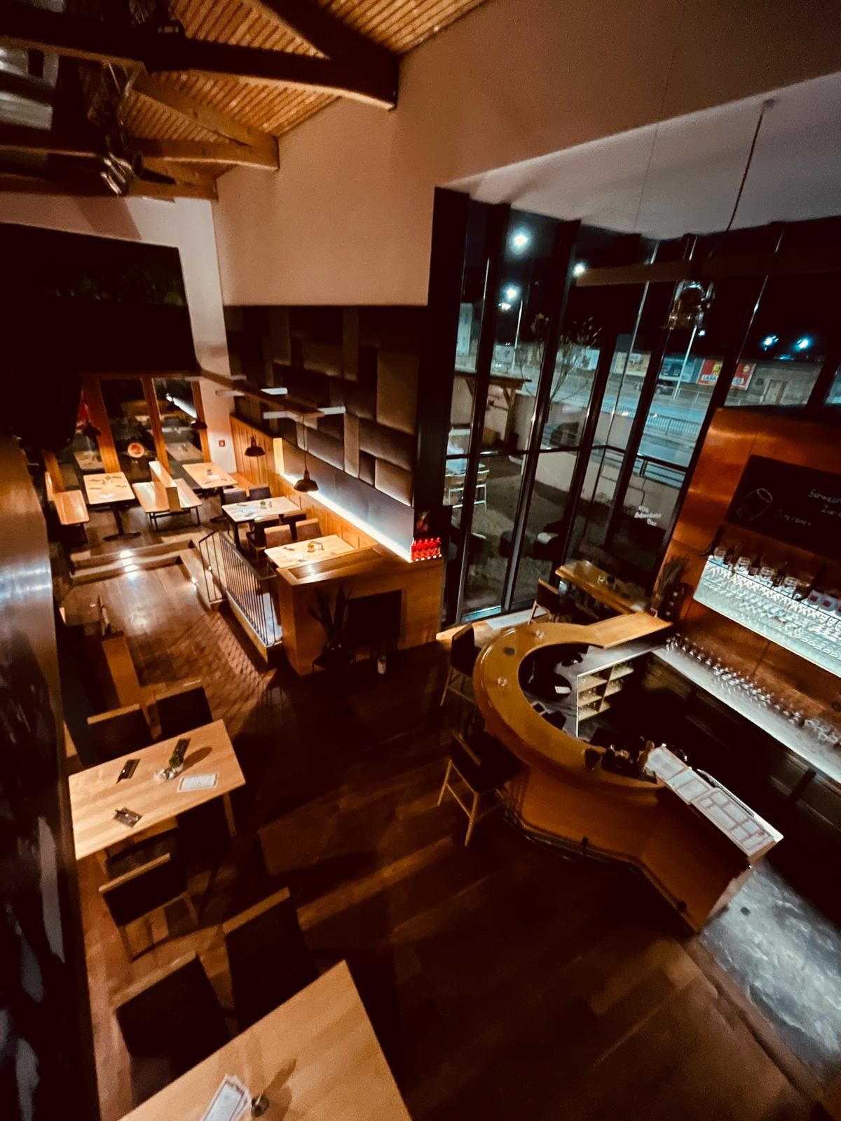 Innenansicht Brauhaus Schwechat bei Nacht mit Holztischen und einer Bar.