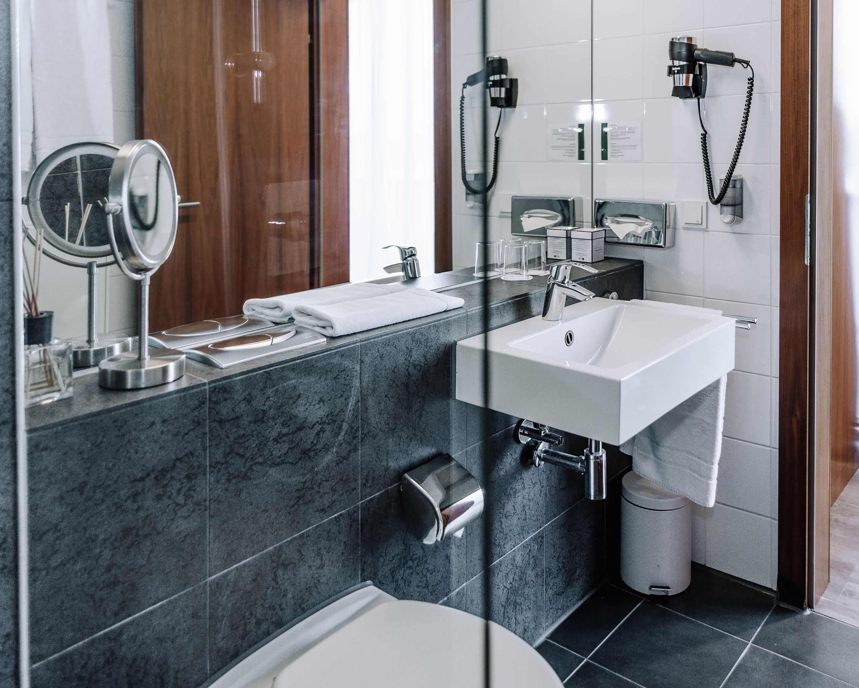 Modernes Hotelbadezimmer mit Waschbecken, Spiegel und Handtüchern.