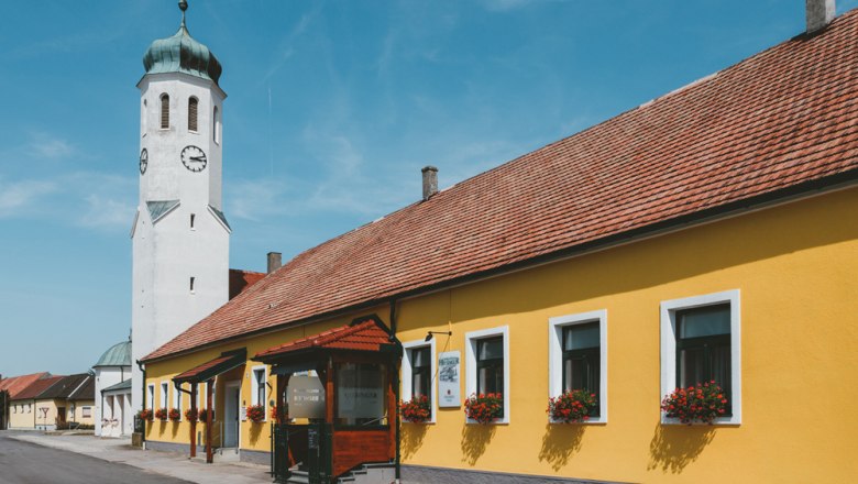 Gelbes Gebäude mit Kirchturm und blauen Himmel in einer Stadtansicht.
