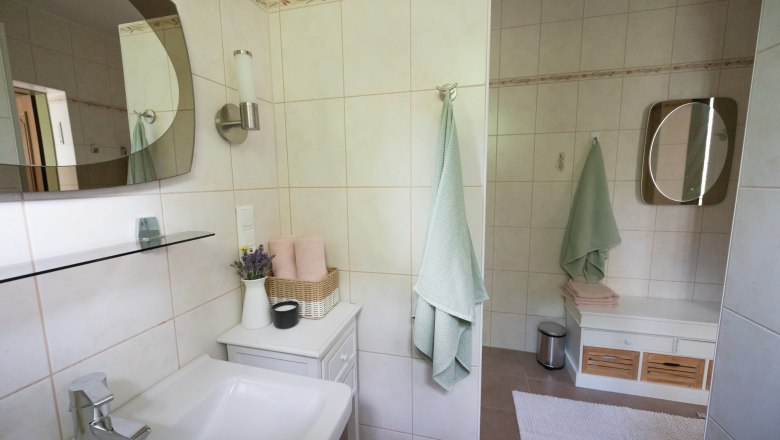 Modernes Badezimmer mit Waschbecken, Spiegel, Handtüchern und Dekoration.