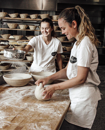 Zwei Frauen backen in einer Bäckerei und kneten Teig.