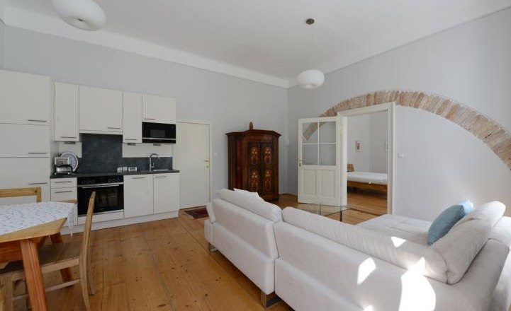 Helles Wohnzimmer mit Küche, Sofa und Esstisch.