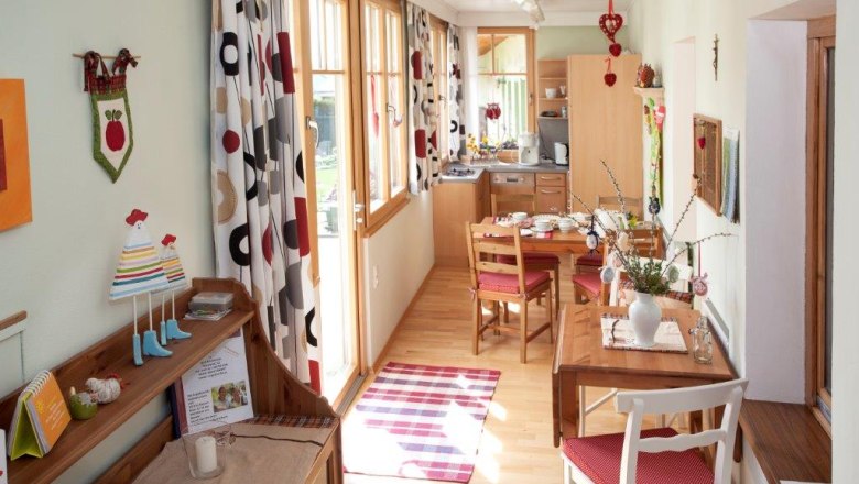 Gem&uuml;tliche Ferienwohnung mit Holzm&ouml;beln, Esstisch und dekorativen Vorh&auml;ngen.