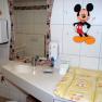 Kinderfreundliches Badezimmer mit Mickey-Mouse-Dekor und Wickeltisch.