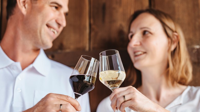 Ein Mann und eine Frau sto&szlig;en mit Weingl&auml;sern an.