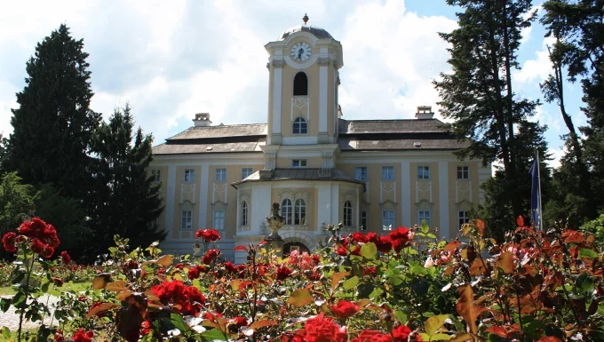 Schloss Rosenau mit bl&uuml;henden roten Rosen im Vordergrund.
