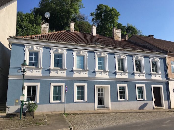 Blaues historisches Gebäude mit weißen Fensterrahmen und Ziegeldach.