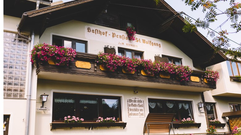 Gasthof-Pension St. Wolfgang mit Blumen geschmücktem Balkon in Kirchberg am Wechsel.