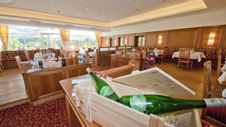 Innenansicht eines eleganten Restaurants mit Holzm&ouml;beln und Weinflaschen.