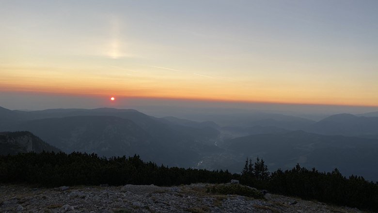 Sonnenaufgang über den Bergen am Jakobskogel mit orangefarbenem Himmel.