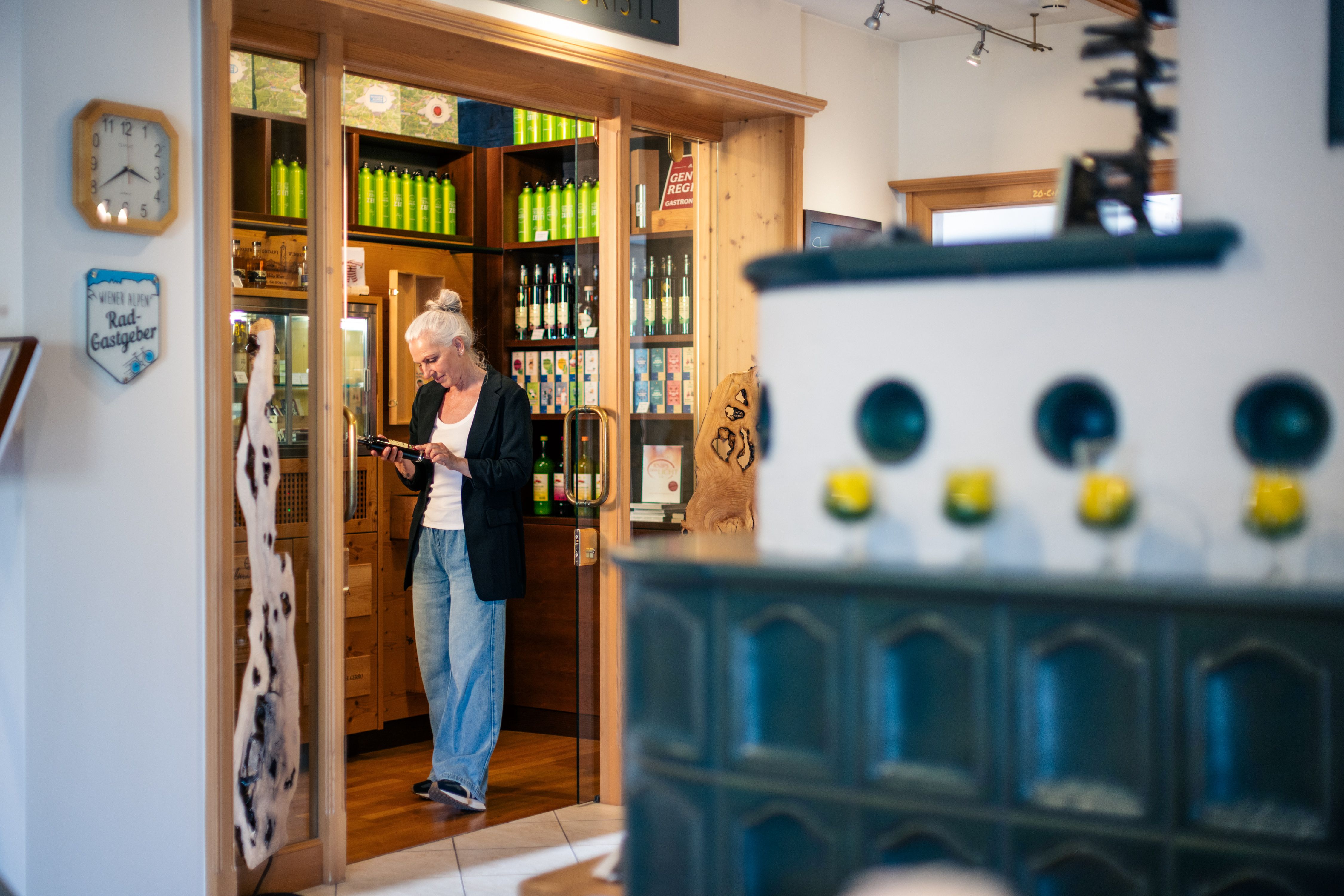 Eine Frau steht in einem Hotelshop und betrachtet eine Flasche in einem Regal mit Getränken.