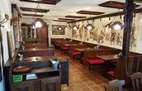Innenansicht einer traditionellen Buschenschank mit Holzmöbeln und Wandmalereien.