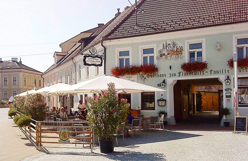 Außenansicht eines traditionellen Gasthauses mit Terrasse und Sonnenschirmen.