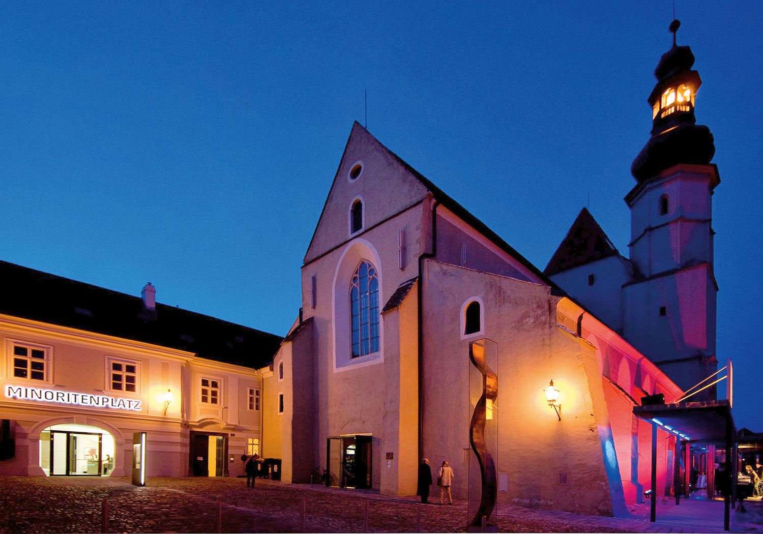 Außenansicht der beleuchteten Minoritenkirche in Krems bei Nacht.