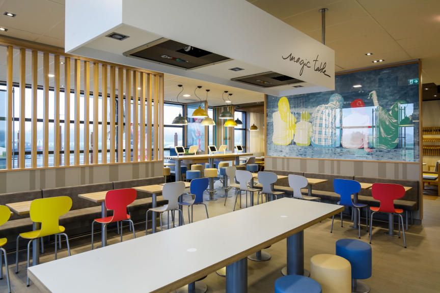 Innenansicht eines modernen McDonald's Restaurants mit bunten Stühlen und Tischen.