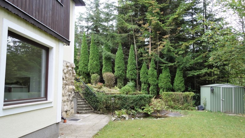 Garten mit Rasen, B&auml;umen und einem Schuppen.