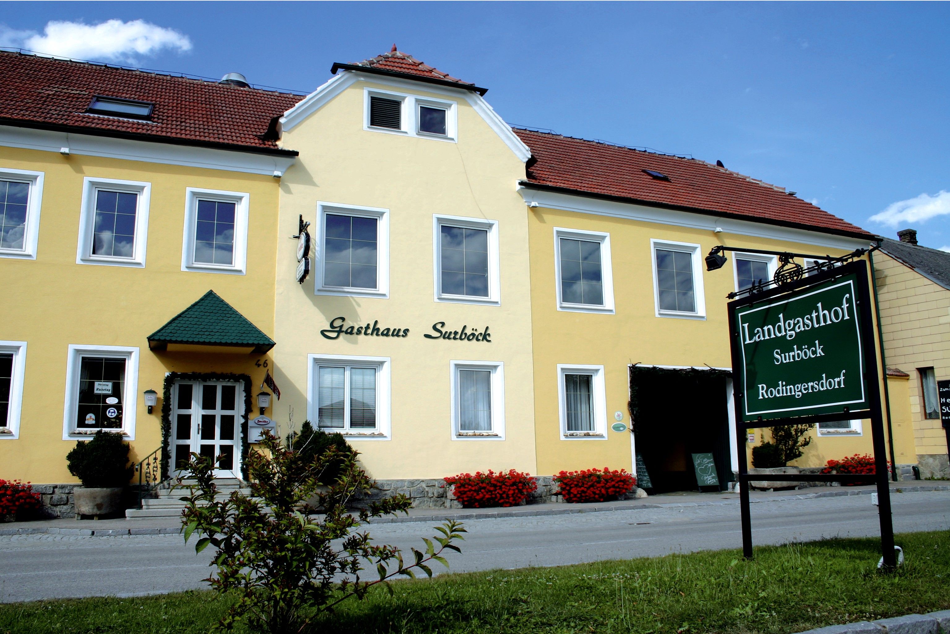 Gelbes Gebäude mit der Aufschrift 'Gasthaus Surböck' und einem grünen Schild 'Landgasthof Surböck Rodingersdorf'.