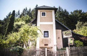 Ein kleiner Turm mit Holzzaun und Bäumen im Hintergrund.