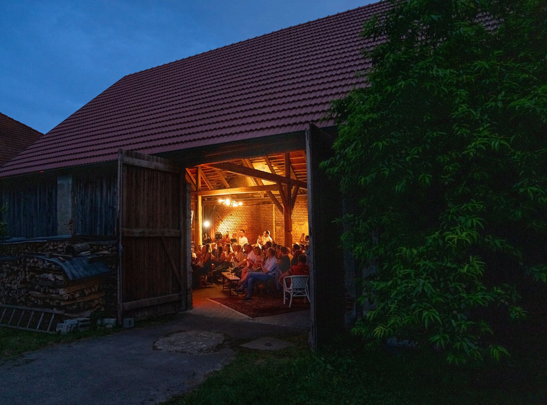In der warmen Abenddämmerung versammeln sich Menschen in einem einladenden, rustikalen Ambiente, um die Köstlichkeiten der Region zu genießen. Das sanfte Licht der Lampen taucht den Raum in eine gemütliche Atmosphäre, während die Klänge von fröhlichem Lachen und angeregten Gesprächen die Luft erfüllen.