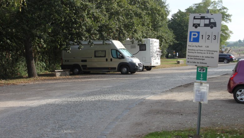 Wohnmobilstellplatz, © Hans Huysza Wohnmobilstellplatz mit zwei geparkten Wohnmobilen und einem Hinweisschild.