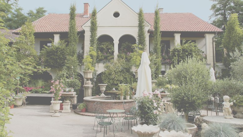 Ein gepflegter Garten mit einem eleganten Gebäude im Hintergrund, umgeben von Pflanzen und Blumen.