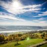 Panoramablick auf eine Flusslandschaft mit gr&uuml;nen Feldern und blauem Himmel.