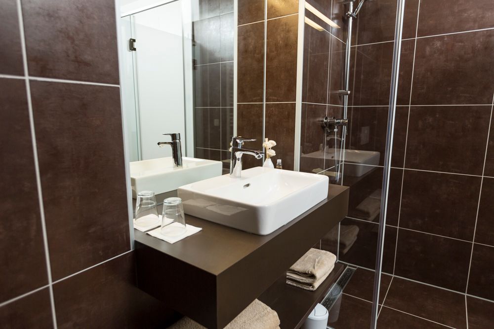 Modernes Badezimmer mit Waschbecken, Spiegel und Dusche.