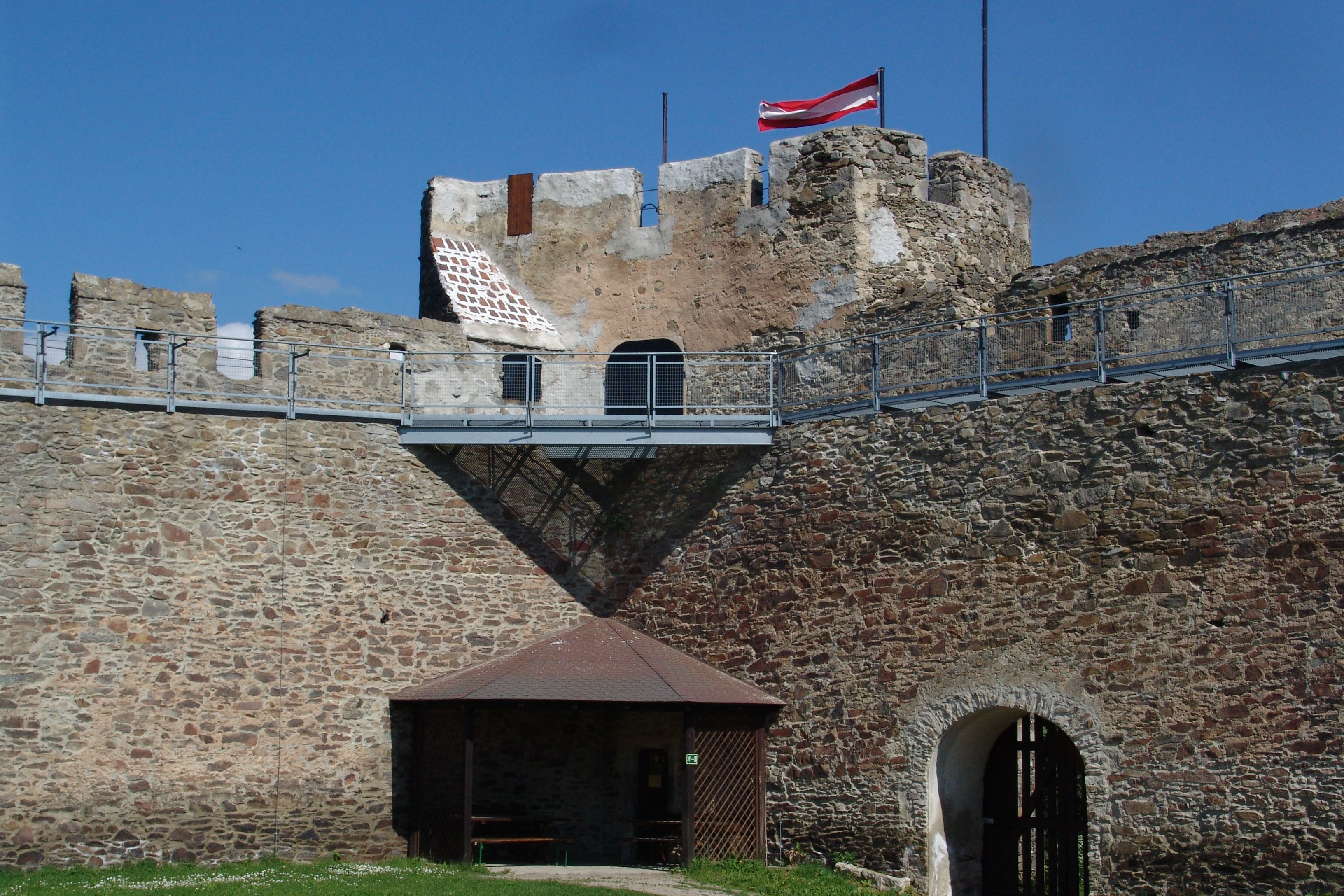 Alte Steinmauer mit österreichischer Flagge auf einem Turm.