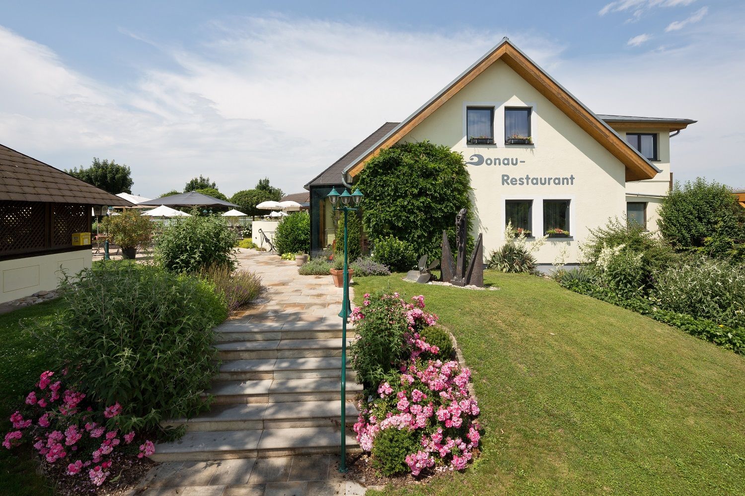 Ein Restaurant mit Garten und Terrasse, umgeben von Blumen und Büschen.