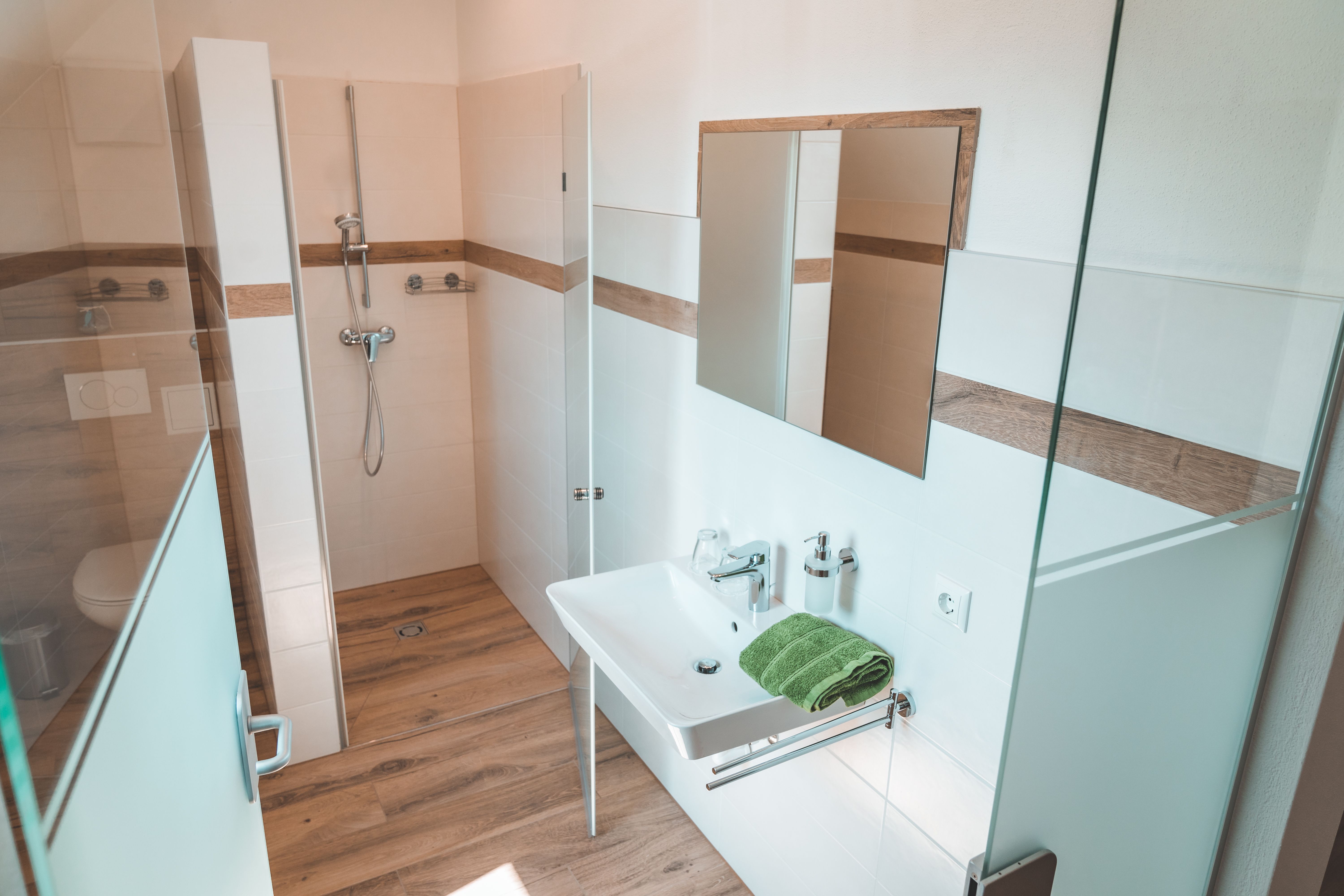 Modernes Badezimmer mit Dusche, Waschbecken und Spiegel.