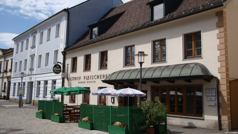 Gasthaus Fleischerei Hirsch mit Au&szlig;enterrasse und Sonnenschirmen.