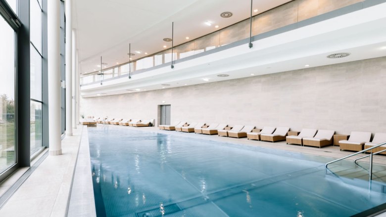 Innenansicht eines modernen Spa-Bereichs mit Pool und Liegest&uuml;hlen.