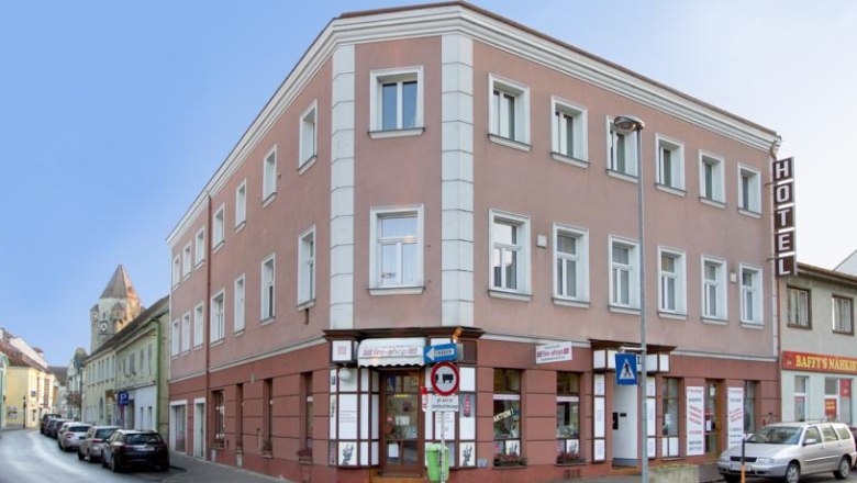 Hotel, © Hotel zu Sonne Dreistöckiges Hotelgebäude an einer Straßenecke mit Autos und Geschäften.